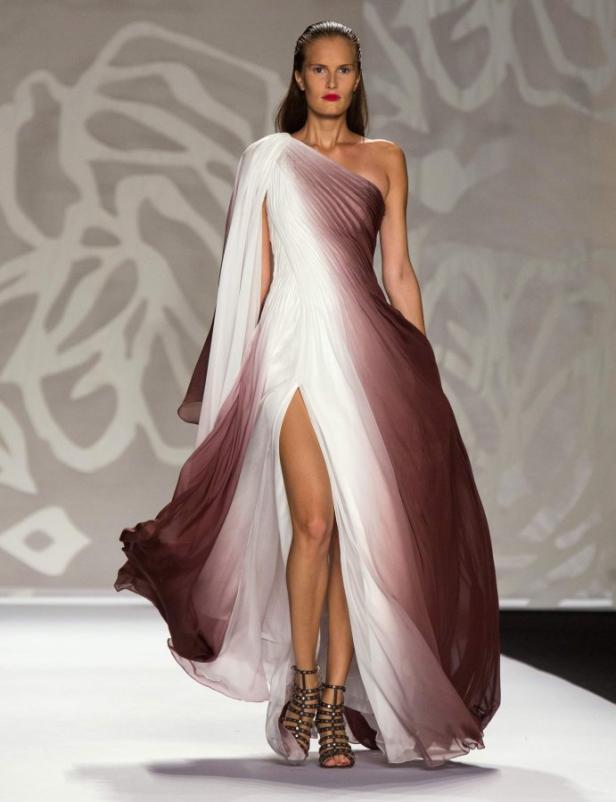 Eine Frau präsentiert ein langes, farblich abgestuftes Kleid mit Beinschlitz auf dem Laufsteg.