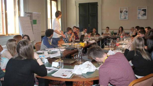 Eine Gruppe junger Leute sitzt an einem Tisch während einer Präsentation.