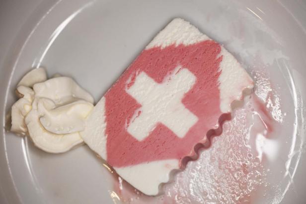 Ein Stück Dessert mit Schweizerkreuz-Muster und einer Beilage Schlagsahne.