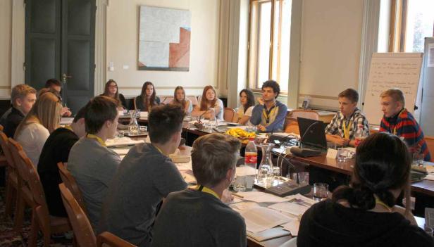 Eine Gruppe junger Leute sitzt an einem Tisch in einem Konferenzraum.