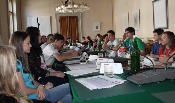 Eine Gruppe junger Leute sitzt an einem Tisch bei einer Konferenz oder einem Seminar.