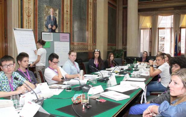 Eine Gruppe junger Leute sitzt an einem Konferenztisch in einem eleganten Raum.