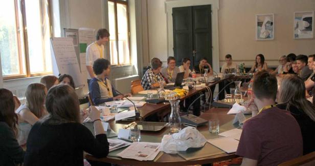 Eine Gruppe junger Leute sitzt an einem langen Tisch in einem Konferenzraum.