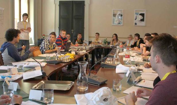 Eine Gruppe junger Leute sitzt an einem Konferenztisch und diskutiert.