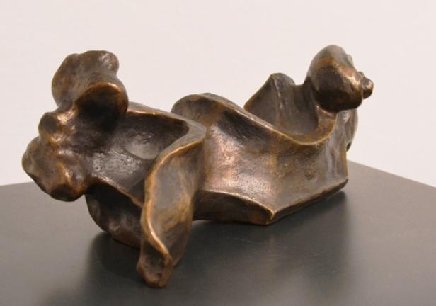 Eine abstrakte Bronzeskulptur auf einer dunklen Oberfläche.