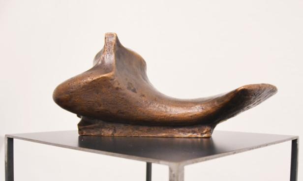 Eine abstrakte Bronzeskulptur auf einem schwarzen Sockel.
