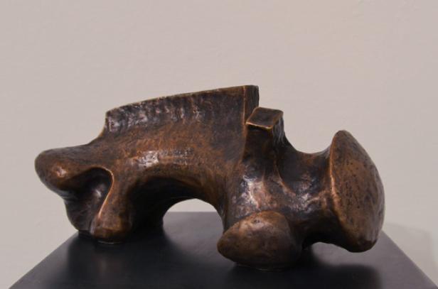 Eine abstrakte Bronzeskulptur auf einem schwarzen Sockel.