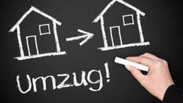 Viele können sich ob der teuren Miete einen Umzug vorstellen Eine Hand zeichnet mit Kreide Häuser und einen Pfeil auf eine Tafel, dazu das Wort „Umzug!“.