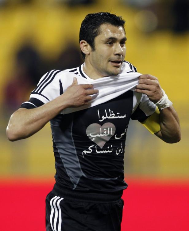 Ein Fußballspieler zieht sein Trikot hoch, das eine arabische Aufschrift und ein Herz zeigt.
