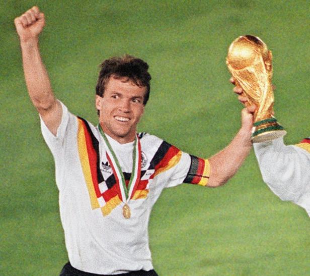 Ein jubelnder deutscher Fußballspieler hält den Weltpokal in die Höhe.