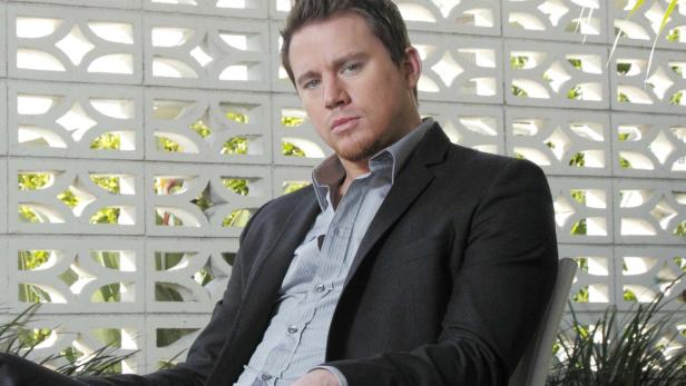 Channing Tatum posiert in einem Anzug vor einer gemusterten Wand.