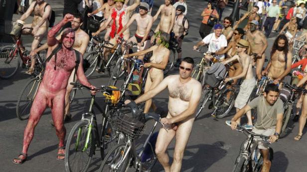 Eine Gruppe nackter Menschen fährt Fahrräder auf einer Straße.