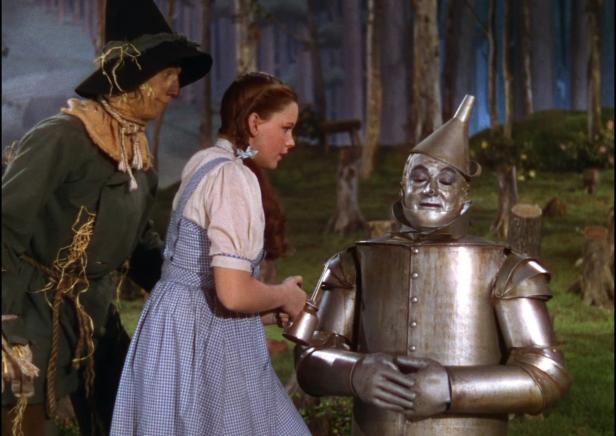Dorothy ölt den Blechmann in „Der Zauberer von Oz“, während die Vogelscheuche zusieht.