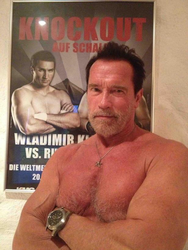 Arnold Schwarzenegger posiert vor einem Boxplakat von Wladimir Klitschko.