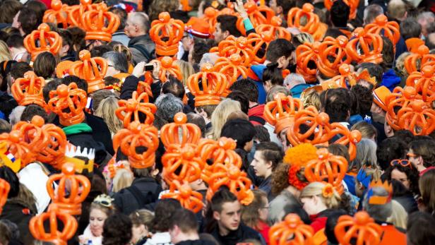 Eine Menschenmenge feiert mit orangefarbenen Kronen auf dem Kopf.