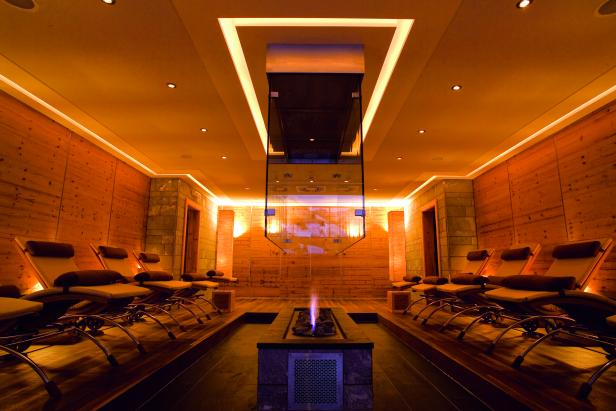 Ein Ruheraum mit Liegen und einem Kaminfeuer in einem Wellnessbereich.