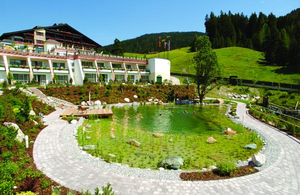 Ein Hotel mit einem naturnahen Schwimmteich im Grünen.