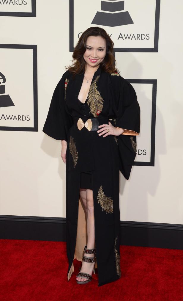 Eine Frau in einem Kimono mit goldenen Federverzierungen auf dem roten Teppich.