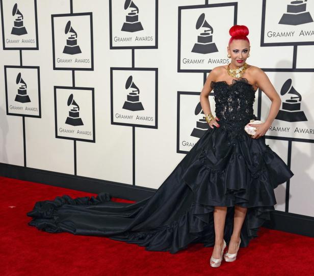Eine Frau in einem schwarzen Kleid posiert vor einer Wand mit „Grammy Awards“-Logos.