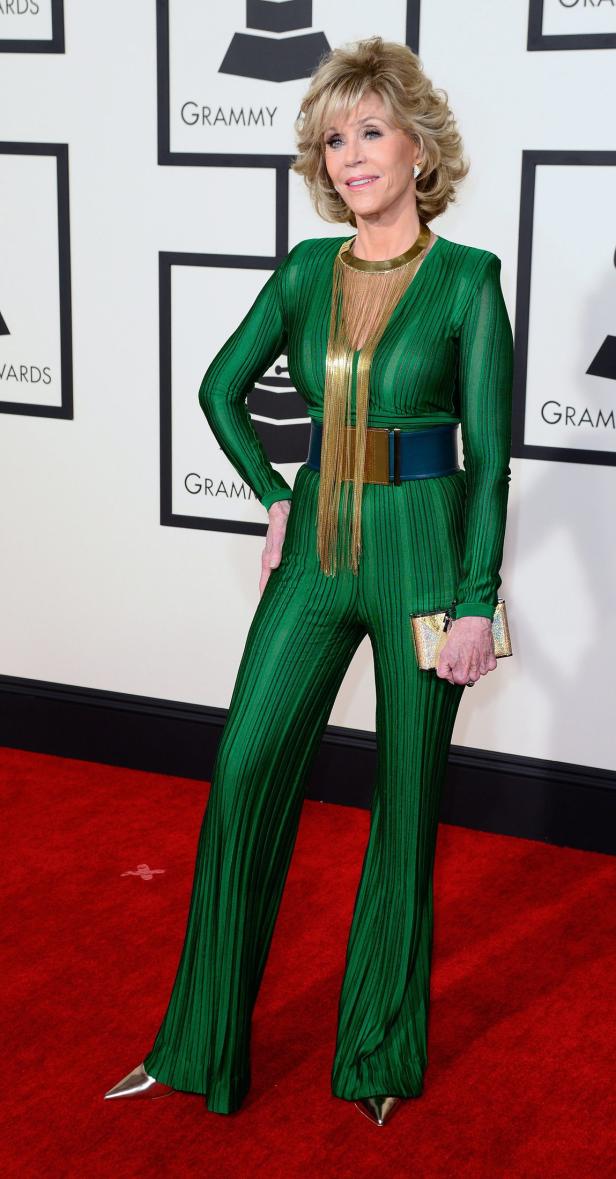 Jane Fonda in einem grünen Overall mit goldenen Accessoires auf dem roten Teppich.