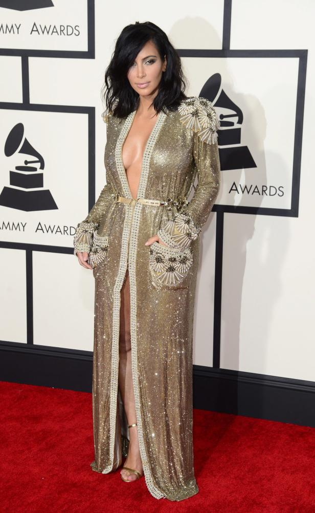 Kim Kardashian in einem goldenen, paillettenbesetzten Kleid auf dem roten Teppich.