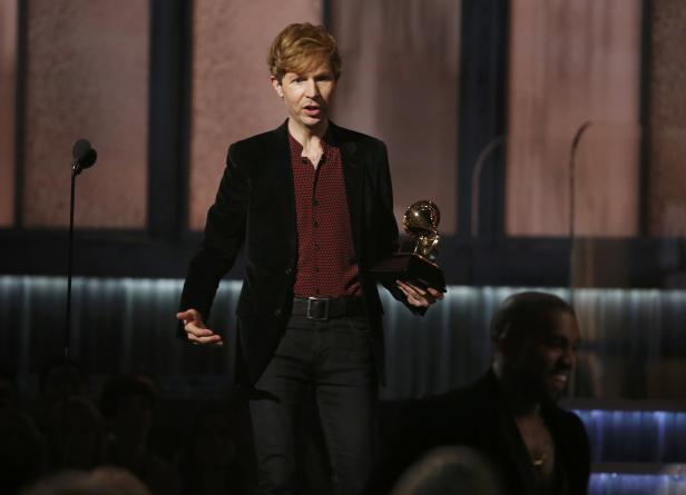 Beck hält eine Grammy-Trophäe auf einer Bühne.