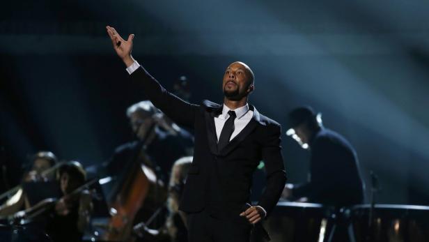 Common tritt mit einem Orchester im Hintergrund auf einer Bühne auf.