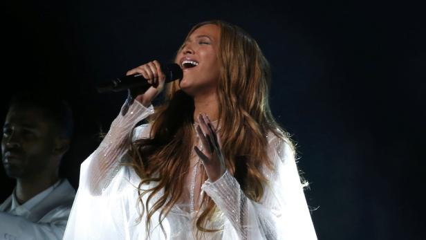 Beyoncé singt in einem weißen Kleid auf der Bühne.