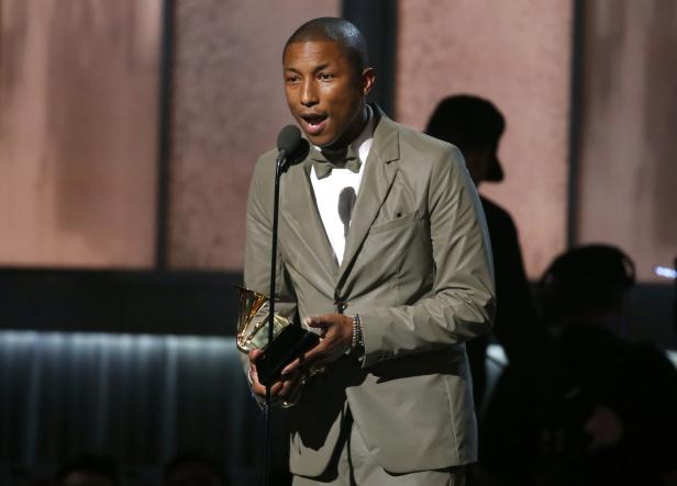 Pharrell Williams hält eine Auszeichnung in der Hand und spricht ins Mikrofon.