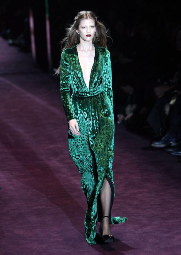 Ein Model präsentiert ein smaragdgrünes, bodenlanges Samtkleid mit Leopardenmuster auf dem Laufsteg.