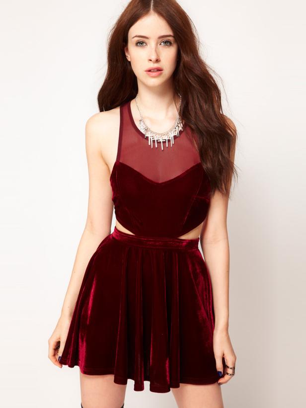 Eine Frau in einem roten Samtkleid mit Cut-Outs und einer silbernen Halskette.