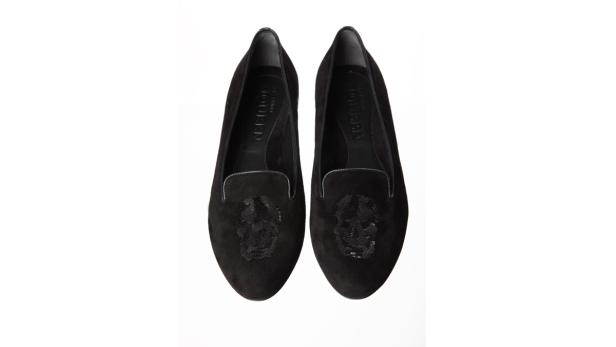 Zwei schwarze Slipper mit Totenkopf-Verzierung stehen nebeneinander.