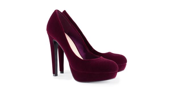 Ein Paar burgunderrote Samt-Pumps mit hohen Absätzen stehen auf einem weißen Hintergrund.