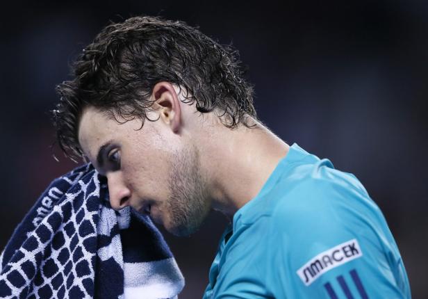 Ein erschöpfter Tennisspieler wischt sich den Schweiß mit einem Handtuch ab.