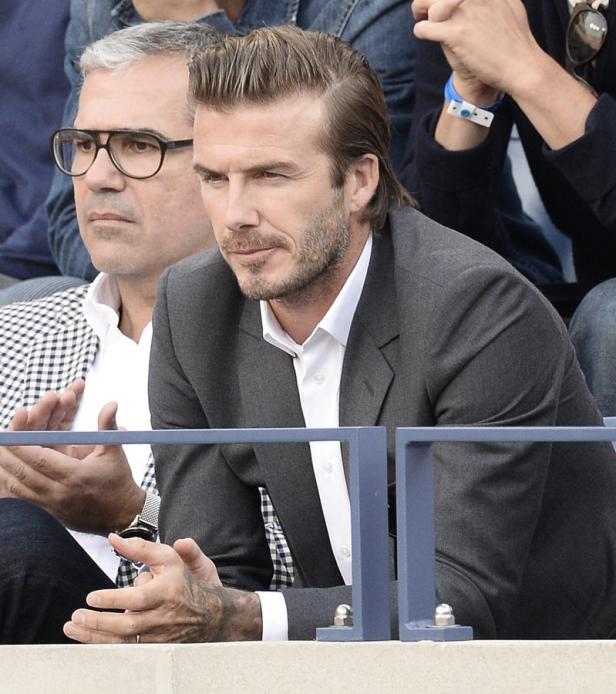 David Beckham sitzt mit einem Mann im Publikum.