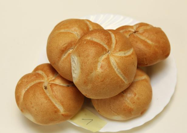 Fünf Kaisersemmeln liegen auf einem weißen Teller.