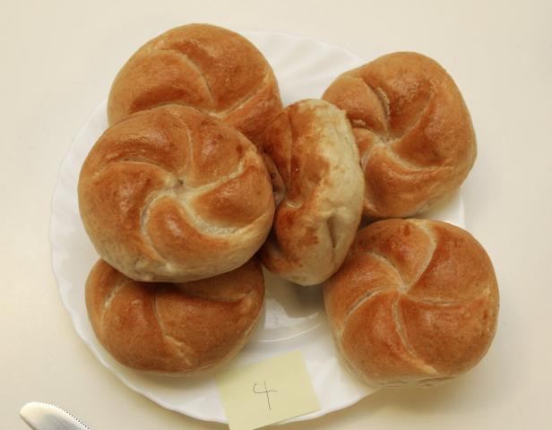 Sechs Kaisersemmeln liegen auf einem weißen Teller.