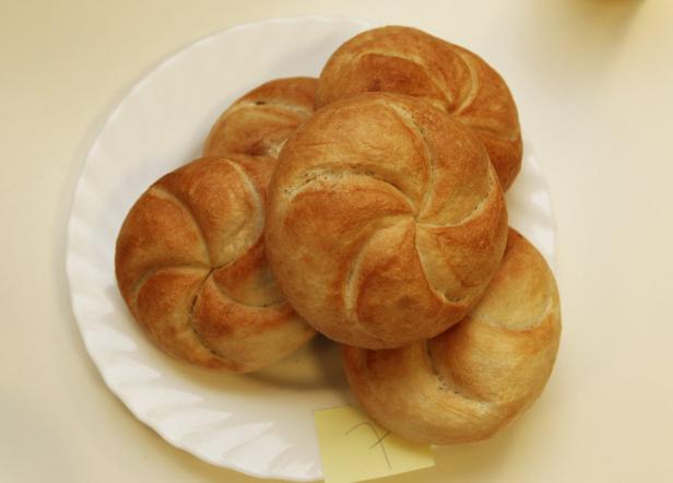 Fünf Kaisersemmeln liegen auf einem weißen Teller.