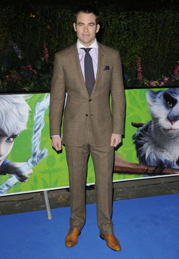 Chris Pine posiert vor einem Poster für den Film „Die Hüter des Lichts“.