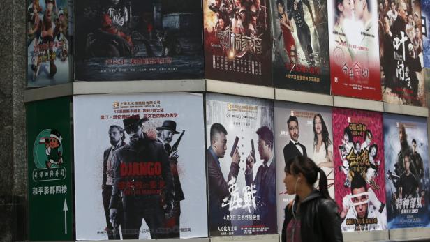 Eine Frau geht an einer Wand mit Filmplakaten vorbei, darunter „Django Unchained“.