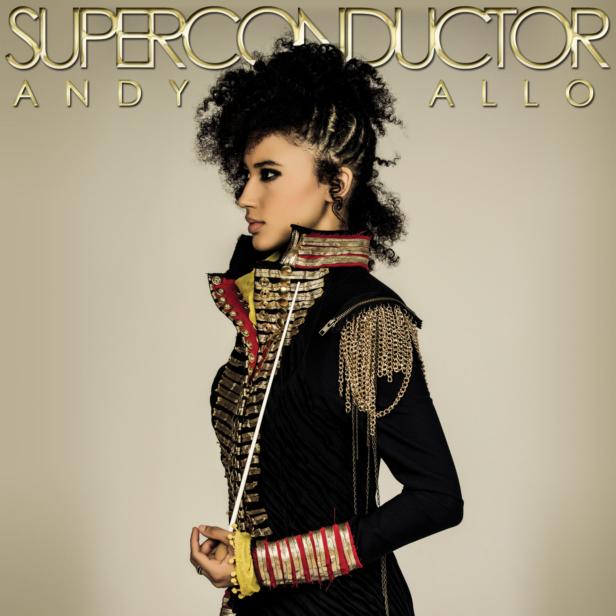 Andy Allo, gekleidet in eine Militärjacke, hält einen Dirigentenstab.