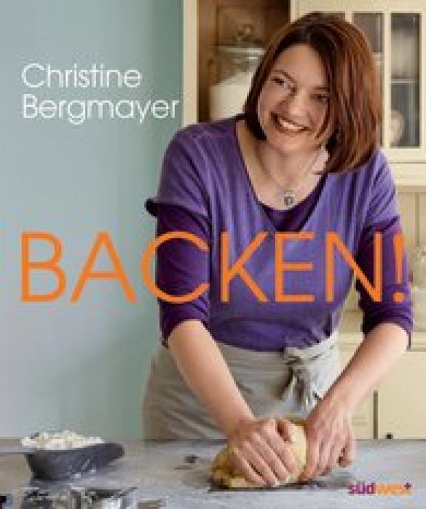 Eine lächelnde Frau knetet Teig vor dem Cover ihres Buches „Backen!“.