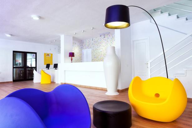 Ein Empfangsbereich mit bunten Möbeln und einer geschwungenen Stehlampe.
