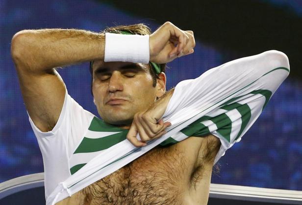 Roger Federer zieht sich sein grünes und weißes Tennis-Shirt aus.