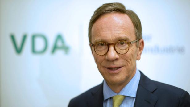 Wissmann Ein Mann mit Brille und Anzug vor einem VDA-Logo.