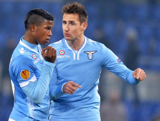 Zwei Fußballspieler von Lazio Rom in ihren hellblauen Trikots unterhalten sich.