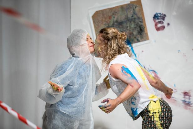 Zwei Personen, mit Farbe bedeckt, scheinen sich zu küssen.