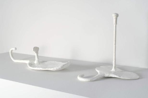 Zwei abstrakte, weiße Skulpturen stehen auf einer weißen Oberfläche.