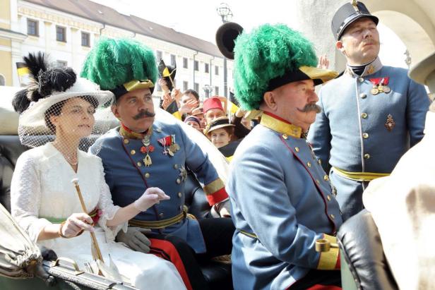 Eine Frau und mehrere Männer in historischen Uniformen und Hüten in einer Kutsche.