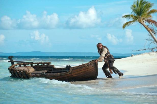 Johnny Depp als Captain Jack Sparrow zieht ein Boot an einem Strand.